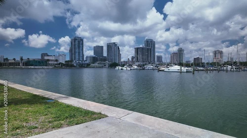 Time lapseView from Albert Whitted Playground into south yacht basin in St. Petersburg, FL. Towards marina, docked boats and Skyline of downtown. Masts and sails against a blue sky. Calm blue water wi
