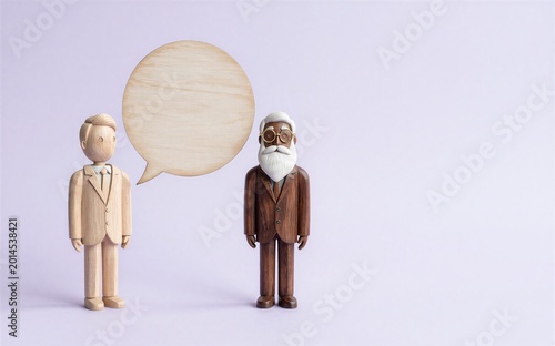Two wooden figurines converse one gesturing with a speech bubble.