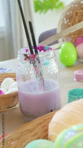Vertical video: Panning camera showing pastel eggs and brushes in purple jar for Easter decor