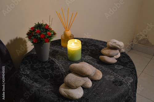 Canvas Print A high perspective from the quarter left angle capturing a burning candle and zen stones placed on a textured green cloth for a home wellness setup