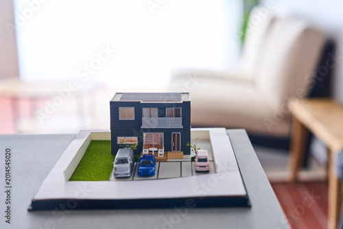 Architectural house model with solar panels and garden on dark base