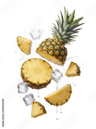 Tableau sur toile Dynamic arrangement of a fresh pineapple, cut into halves and slices, with ice cubes and invigorating water splashes
