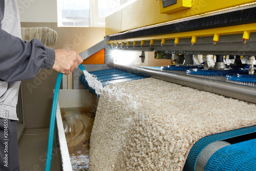 Male worker cleaning carpet on automatic washing machine equipment and dryer in the Laundry room. professional washing service