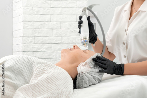 Bild auf Leinwand Young woman receiving laser treatment in cosmetology clinic
