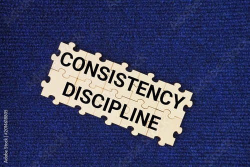 Foto Wooden puzzle with the words consistency and discipline