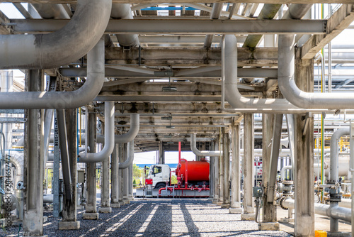 Foto View of a tank truck and facilities at a gas plant LPG loading station seen through industrial pipe rack structures
