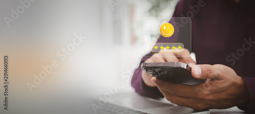 Customer satisfaction survey on smartphone with businessman giving five star rating and happy smiley face icon.