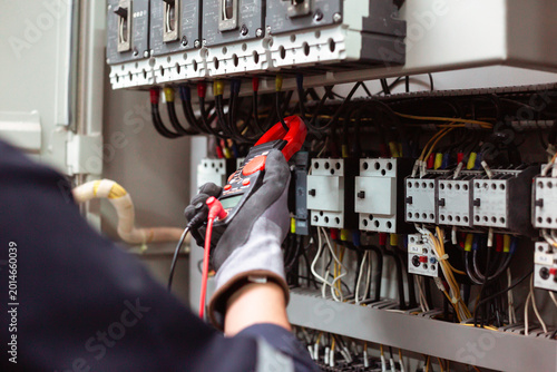 Digital multimeter testing industrial electrical circuits for maintenance.