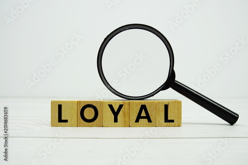 Foto LOYAL alphabet letters with magnifying glass on wooden background