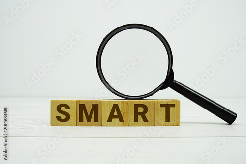 Quadro su tela SMART alphabet letters with magnifying glass on wooden background