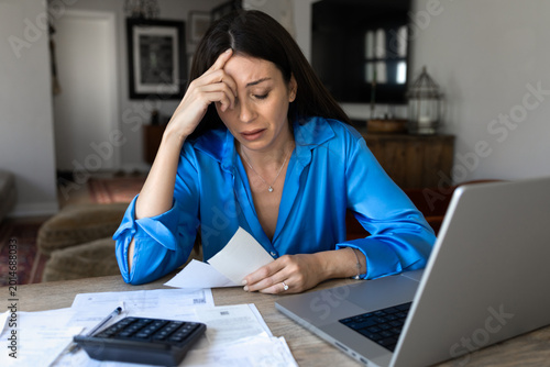 Stressed woman reviewing bills at home, experiences financial pressure, budgeting difficulties and emotional strain caused by high household expenses, lack of money and personal financial crisis, debt
