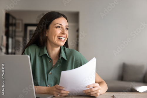 Foto Woman holds papers documents at home office desk, distracted from information re