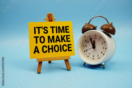 Fotografi It's Time To Make A Choice text with alarm clock on blue background