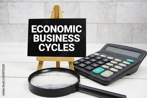 Fotografie Economic Business Cycles text with calculator and magnifying glass