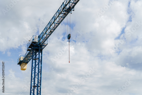 Valokuva Blue construction crane hook and jib against a cloudy sky, representing engineer