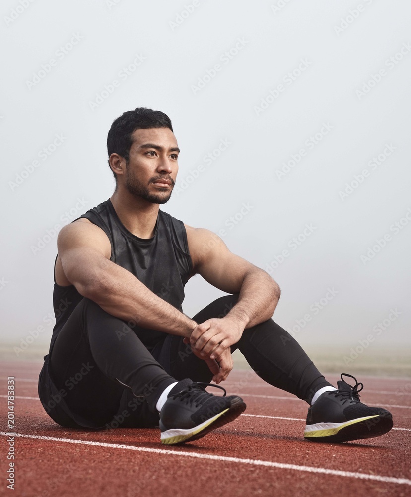 Fototapeta premium Thinking, track and man on floor with race or training idea for sports in mist or fog. Confident, fitness and athlete or runner for competition, tournament and wellness strategy for outdoor workout