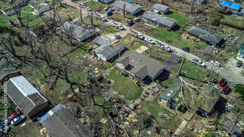 Drone view of residential neighborhood destruction after a tornado with damaged houses and scattered debris.