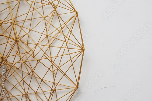 Golden geometric sculpture with intersecting lines against a plain white background