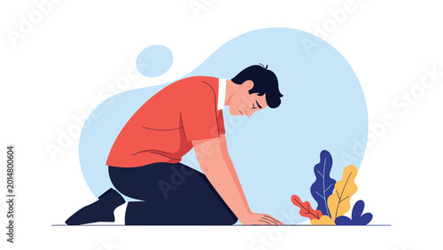 Depressed young man kneeling on the floor with head bowed in deep sadness and despair against a soft abstract blue background.