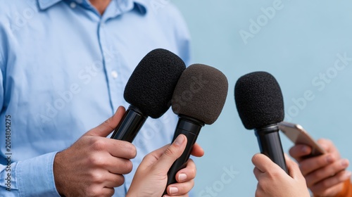 Close up of journalists' hands holding multiple microphones and smartphones for a press interview or media conference.