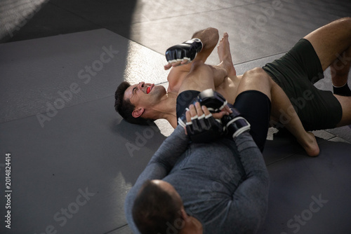 Quadro su tela Diverse male sparring partners grappling on gray mats at dojo, showing mouthguar