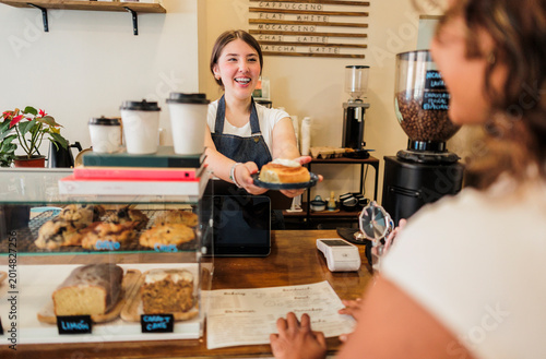 Foto Happy barista serving delicious cinnamon roll to customer