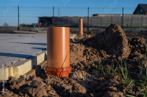 Bilde på lerret Outdoor sewer pipe installation at construction site, PVC drainage outlet in ground near house foundation, plumbing infrastructure work