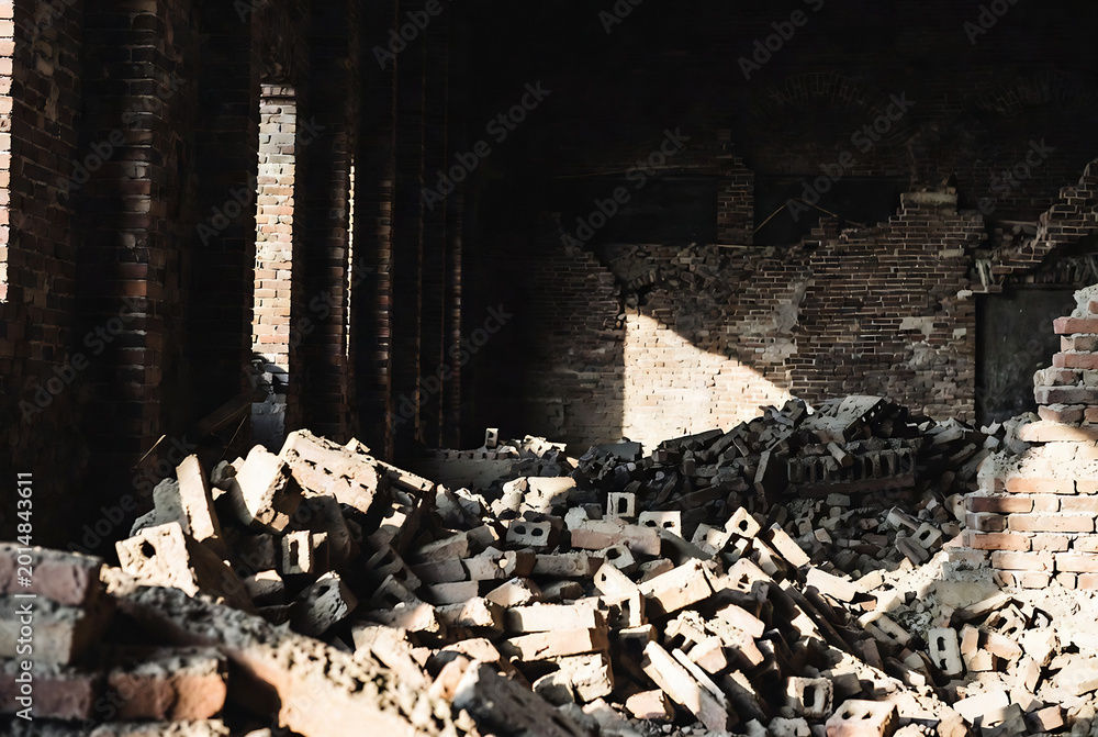 Fototapeta premium Abandoned brick ruins, likely a demolished building or structure, with sunlight illuminating the rubble.