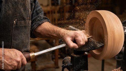 Skilled woodworker shaping a wooden bowl on a lathe, with wood shavings flying and workshop tools visible in the background, showcasing craftsmanship in a rustic environment