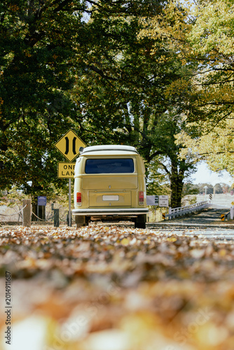 Foto Vintage camper van parked on a quiet autumn road surrounded by colorful trees and fallen leaves capturing retro travel, road trip adventure outdoor lifestyle, freedom, and seasonal nature scenery