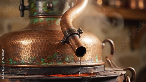 Close up of antique copper alembic still with steam and liquid dripping, traditional distillation process, artisanal production