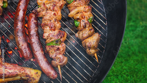  Delicious grilled meat with vegetables sizzling over the coals on barbecue. Grilling in summer with copy space concept.