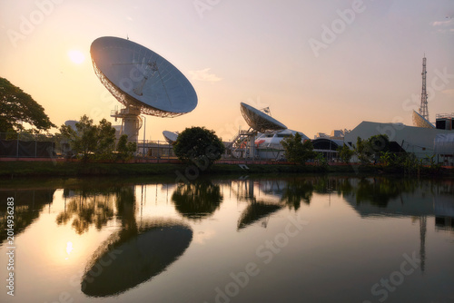 Giant satellite dish antenna station with skyline reflection at sunrise