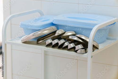 Stainless steel medical bowls on a mobile metal utility trolley