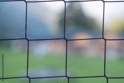 Canvas Print Blurred perspective through a black netting fence, revealing a soft-focus backgr