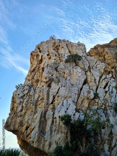 Dramatic limestone rock formation with natural erosion patterns under a clear blue sky. Rugged geology and outdoor landscape suitable for nature, travel, adventure, and strength concepts.
