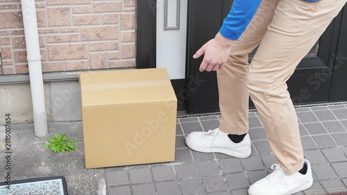 玄関前に荷物を置き配する若い宅配業者　ライフスタイルイメージ
