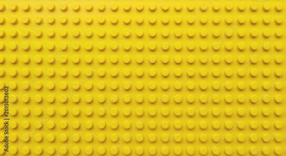 Fototapeta premium Yellow plastic building block plate texture background for kids toys