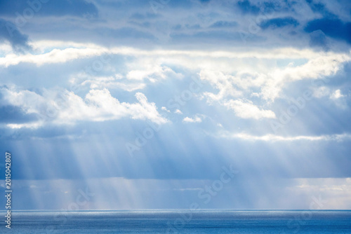 Dramatic ocean landscape with sunbeams piercing through clouds
