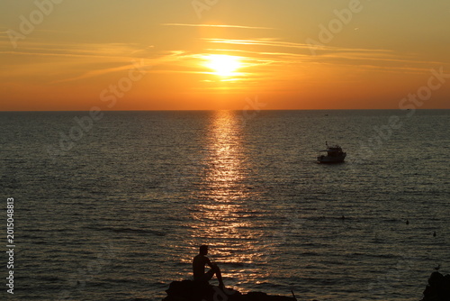 Dopo un bagno, seduto su uno scoglio ad ammirare il tramonto