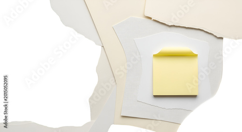 A single yellow sticky note rests on a pile of layered paper sheets with torn edges.