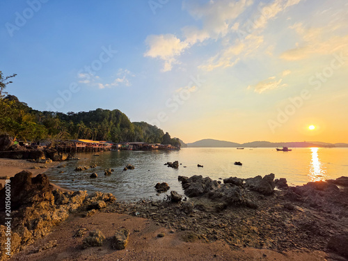 Fotografia Peaceful sunset over tropical island beach with rocky shoreline calm sea water g