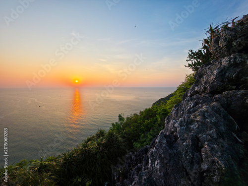 Fotografie Peaceful sunset over ocean horizon viewed from steep rocky cliff with lush green