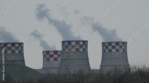 Industrial cooling towers with rising steam in cloudy weather