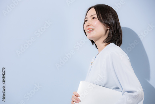 水色背景で腕組みで笑顔の女性のポジティブポートレート、カッコイイ女性の信頼と自信のイメージ　未来や目標を見上げる