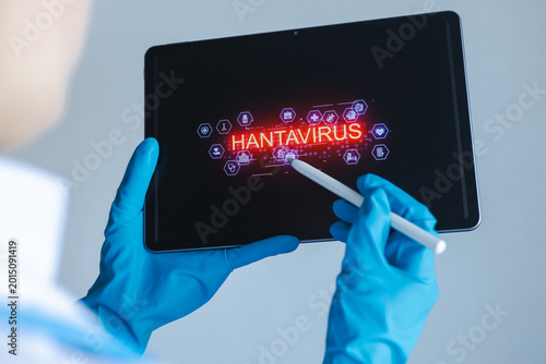 Person using a tablet to display information about hantavirus and related data in a lab setting during daytime