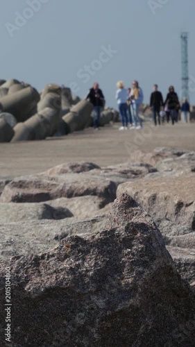 Vertical shot of jagged coastal rocks with blurred people in background