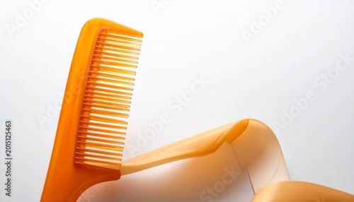 A close‑up of an orange plastic comb with fine teeth and a curved handle, placed against a light background, glossy surface reflecting soft light, minimalist composition emphasizing color and texture.