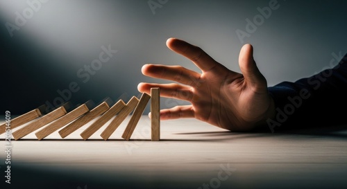Hand stopping falling dominoes to prevent chain reaction 4.