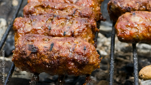Tableau sur toile Close-up of traditional Romanian mici (mititei) grilling on a charcoal barbecue